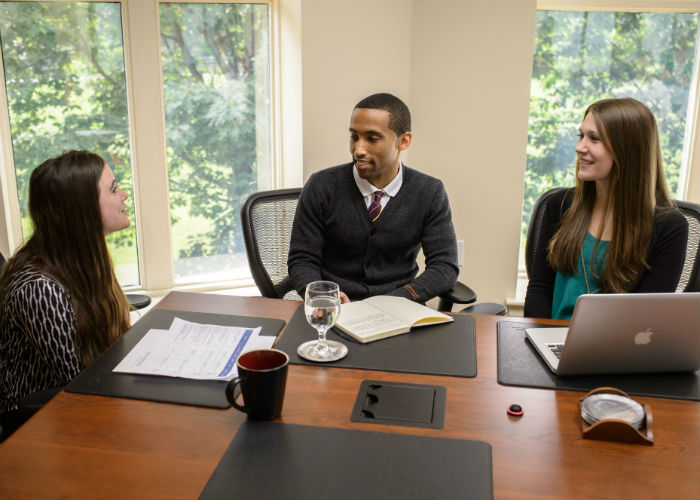 A group of young professionals meet at a conference table.