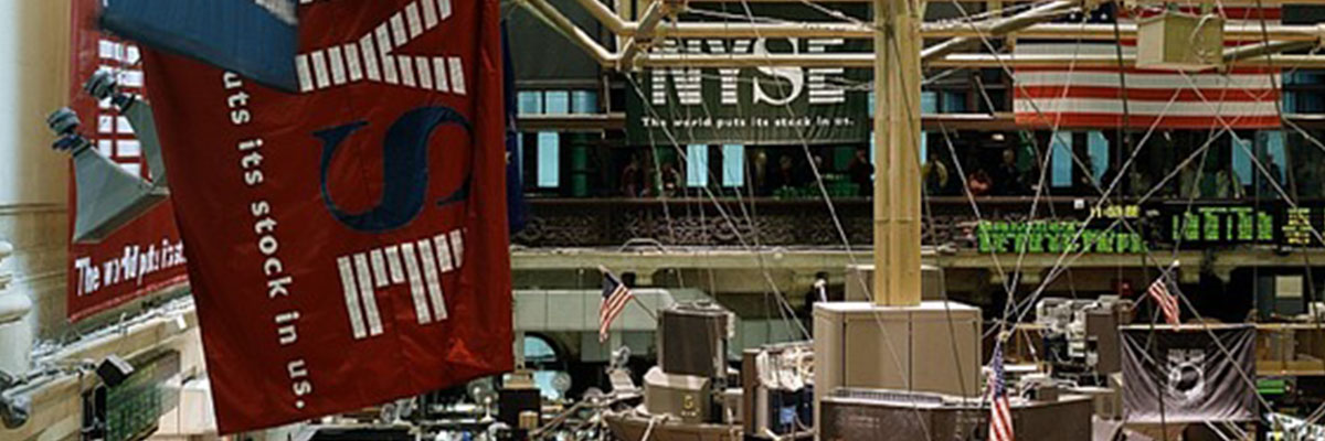 At the New York Stock Exchange above the trading floor, banners and American flags punctuate the scrolling stock tickers.