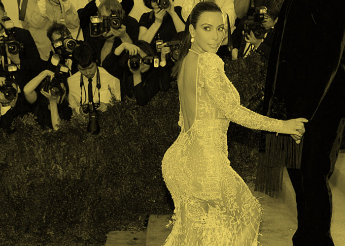Reality TV star Kim Kardashian turns to look over her shoulder on the red carpet, surrounded by paparazzi