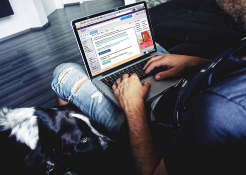 Dog sitting next to man writing an email